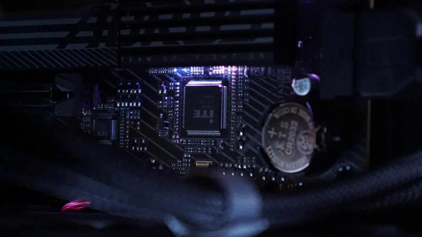 Coin-shaped CMOS battery on a motherboard inside a dark PC