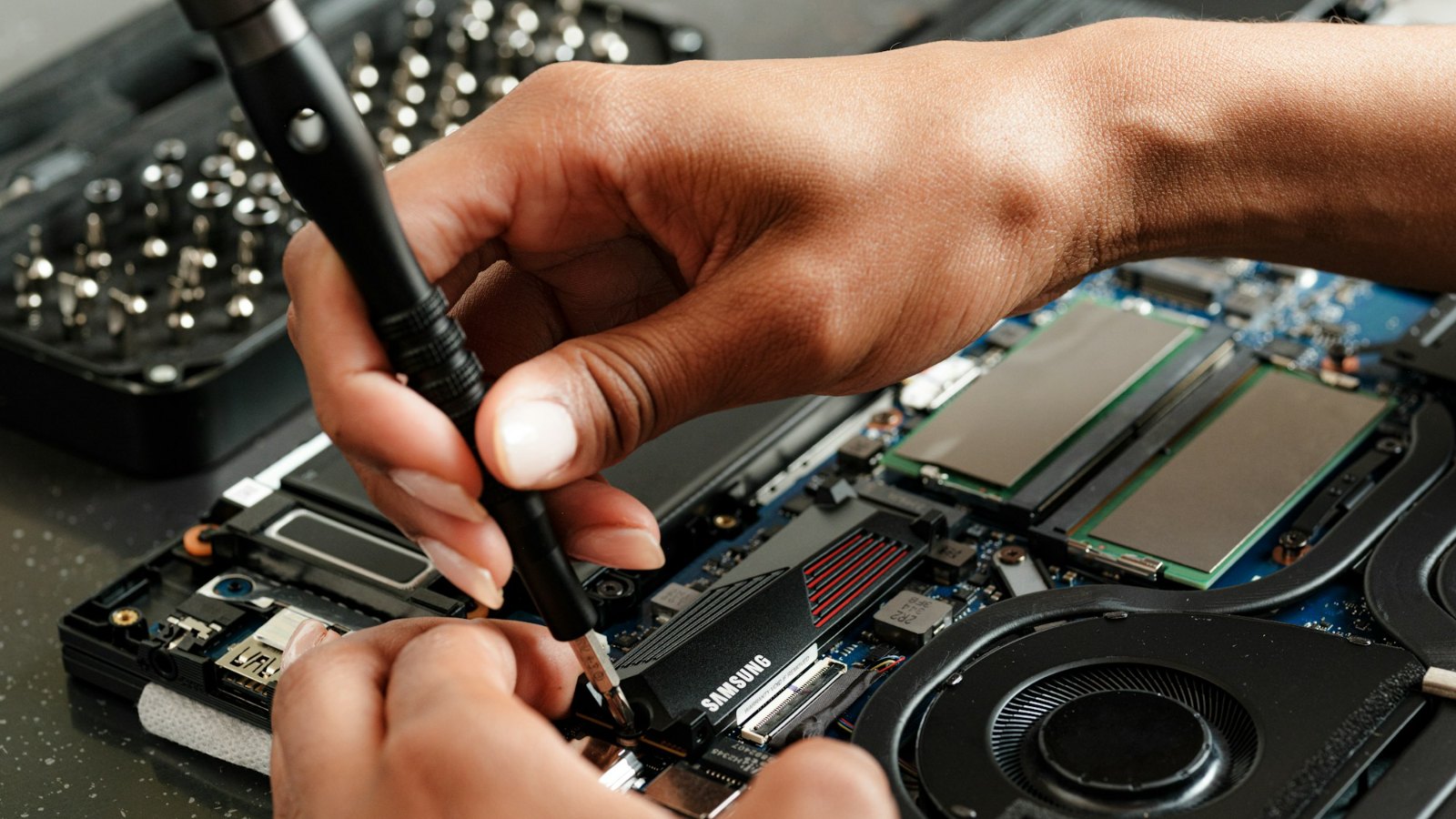 Hands repairing a computer with a precision screwdriver