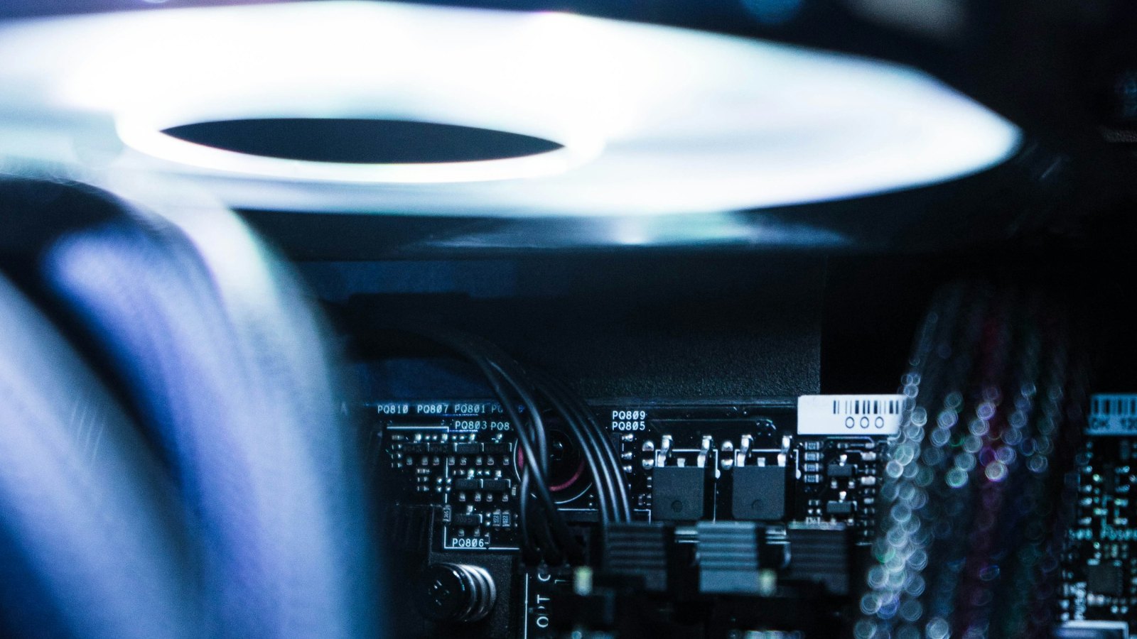 A lit cooling fan above the electronics inside a PC