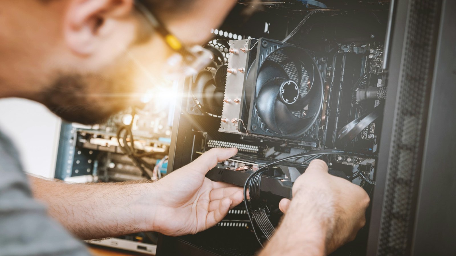 A person working inside an open desktop PC
